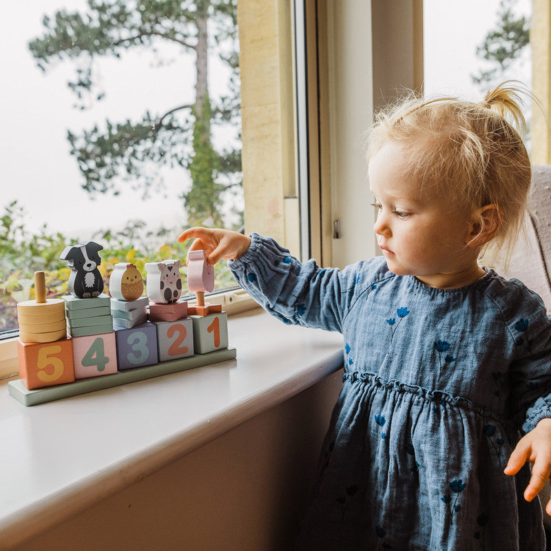 Juego de contar granja en uso, apilando bloques numerados y animales, aprendizaje jugando