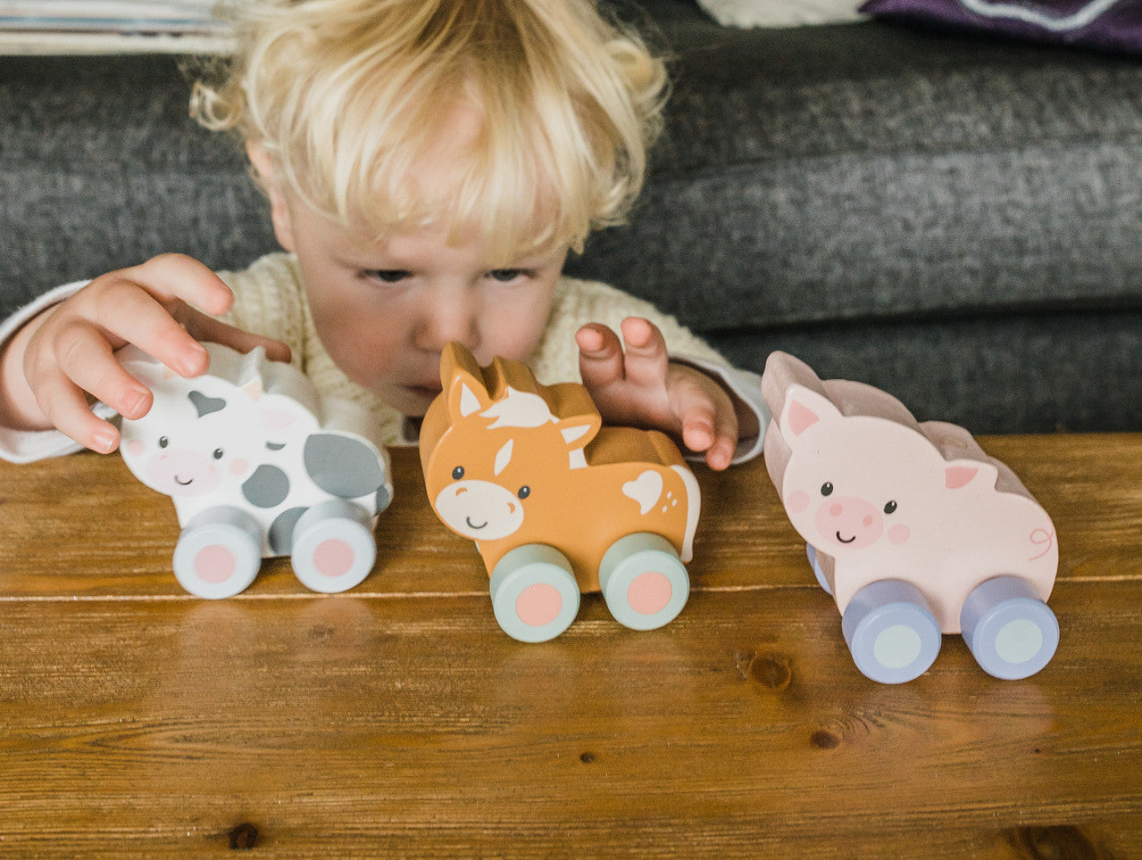 Vaca de madera con ruedas, foto lifestyle del juguete de empuje en uso por niños